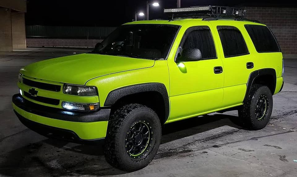 A Chevy Tahoe painted green with Liners on the fenders